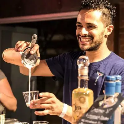 Team member pouring a cocktail during a mixology class. The event fosters teamwork and creativity as participants learn the art of cocktail crafting while enjoying a fun, interactive experience.