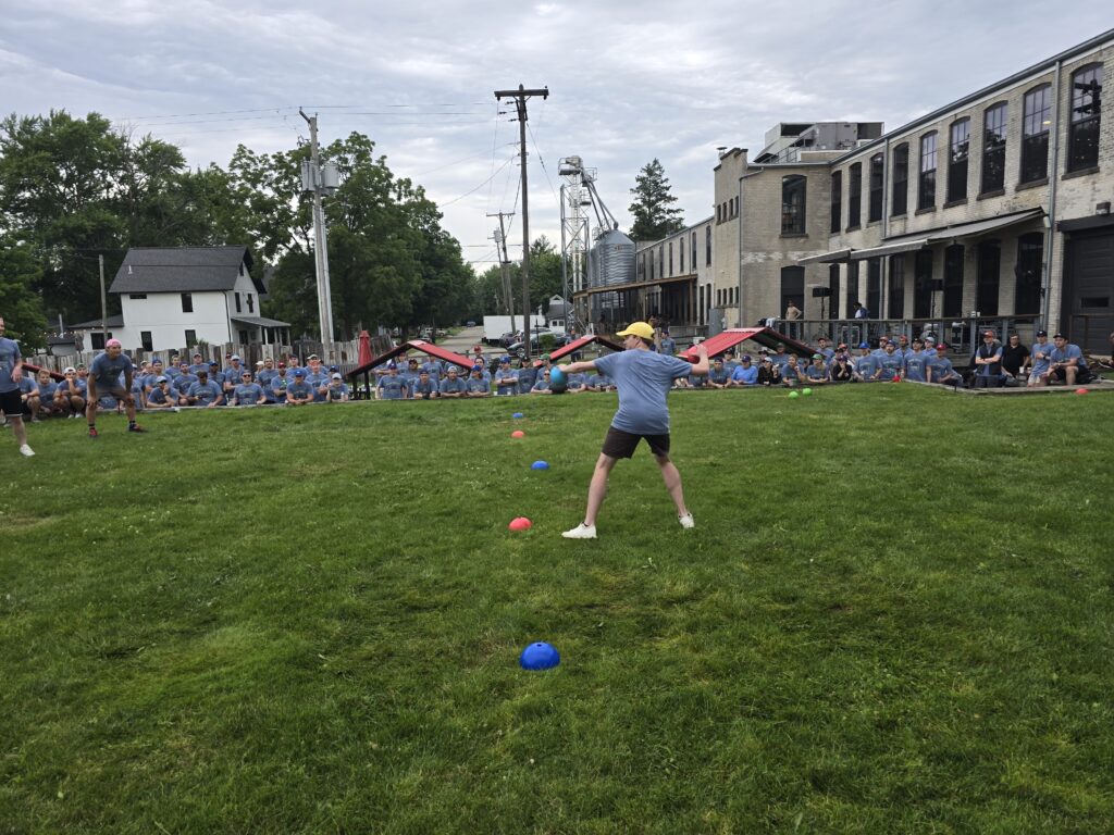 A group of people are participating in an outdoor activity on a lawn. It looks like a fun and engaging team building challenge.