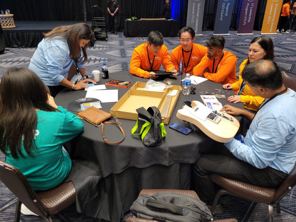 Team members collaborate around a table, assembling and decorating their guitar at the Charity Guitar Build team building event, combining creativity with a meaningful cause.