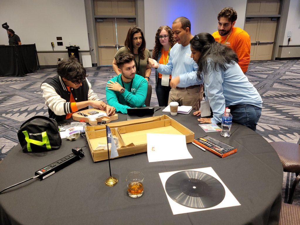 Group of team members working together on guitar assembly and design during the Charity Guitar Build team building event, focused on creativity and collaboration for a charitable cause.