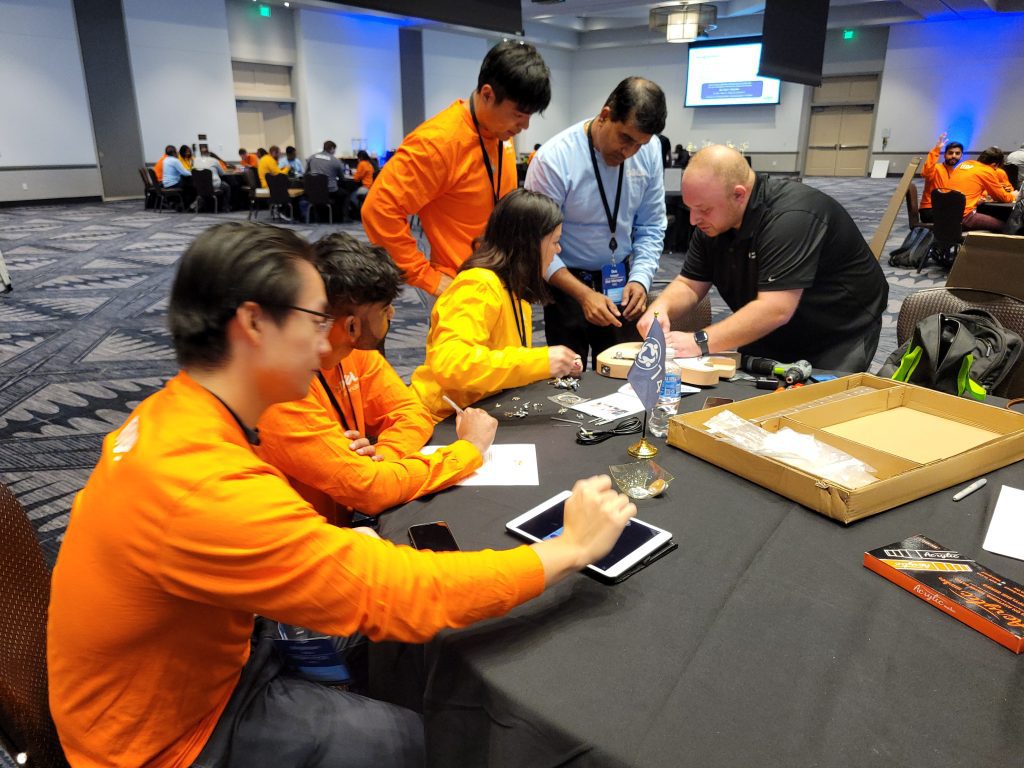 Team members collaborate on guitar assembly at the Charity Guitar Build event, engaging in hands-on teamwork and creativity to support a charitable cause.