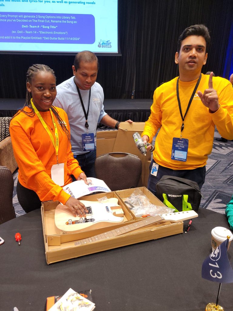 Team members discuss the guitar assembly process during the Charity Guitar Build team building event, bringing creativity and collaboration to their project.