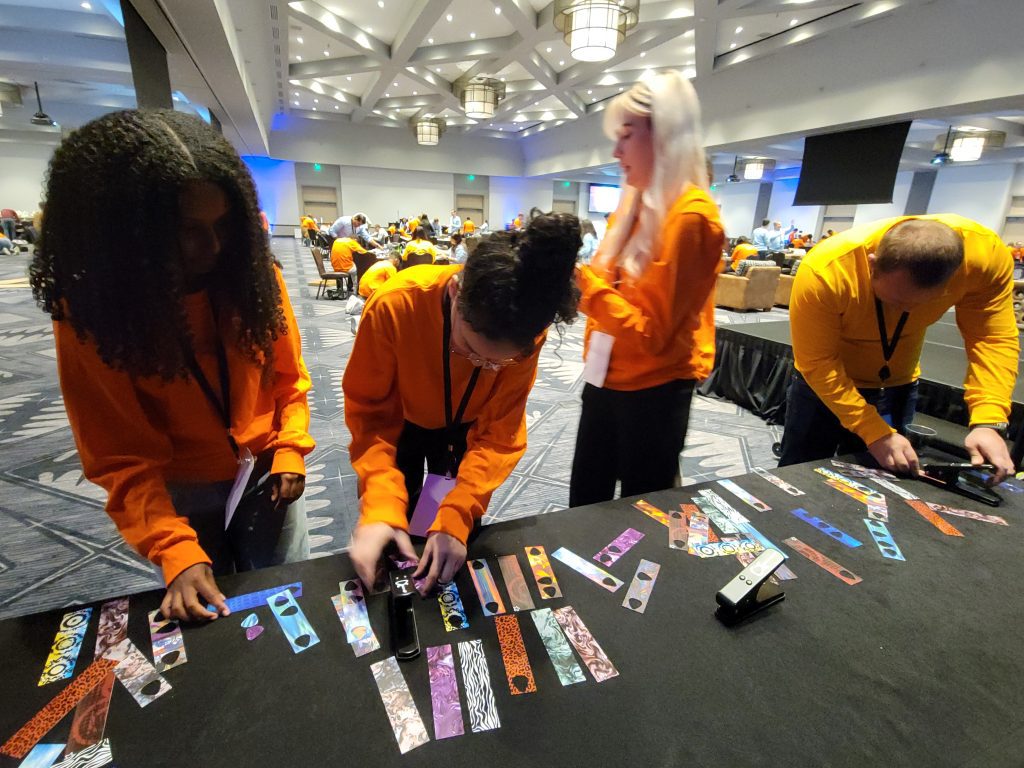 Participant add creative decorations, such as picks, to go with the guitar donations during the Guitar Build CSR team building program.