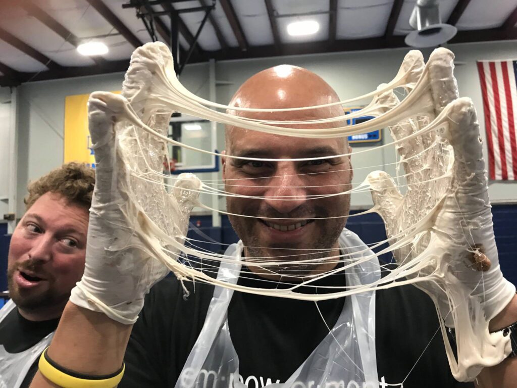 A man wearing gloves stretches melted marshmallow during The Chocolate Challenge team building event.