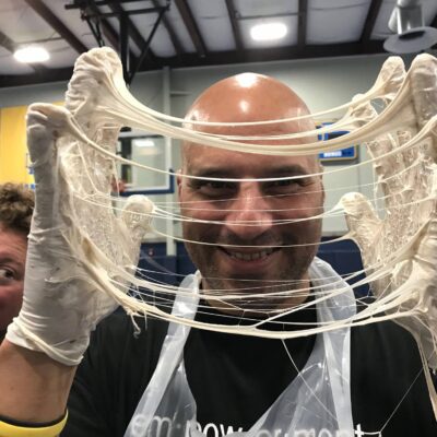 A man wearing gloves stretches melted marshmallow during The Chocolate Challenge team building event.