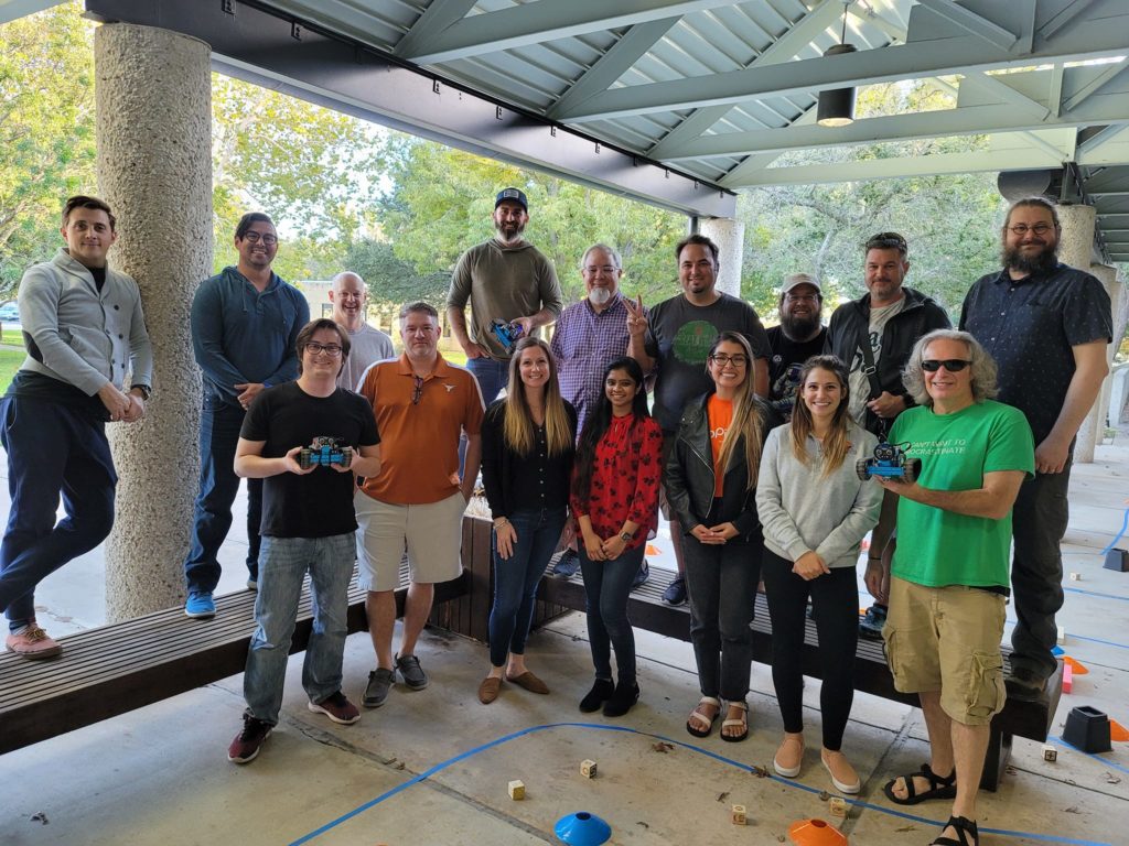 A group of participants pose together after a successful outdoor team building event, proudly holding their completed robots.