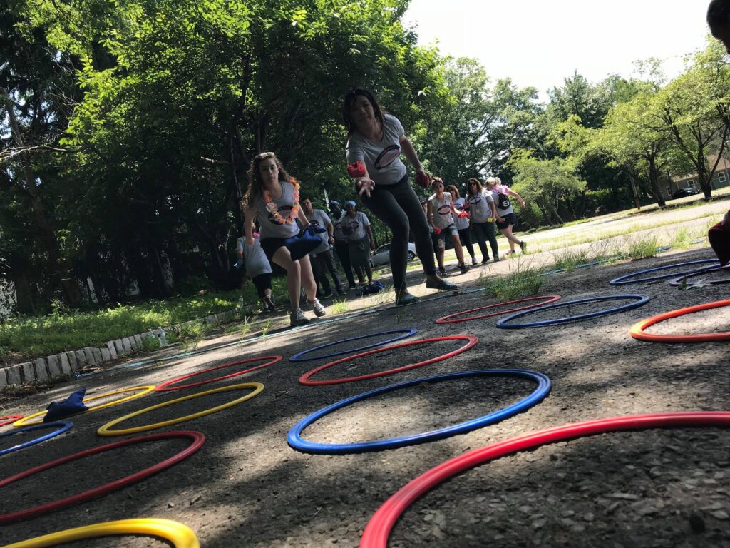 Participants toss objects into colored rings during an outdoor team building challenge, aiming to outscore their competition.