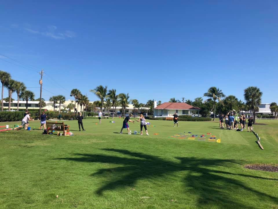 Participants engage in an outdoor team building activity, competing in various challenges on a sunny golf course.