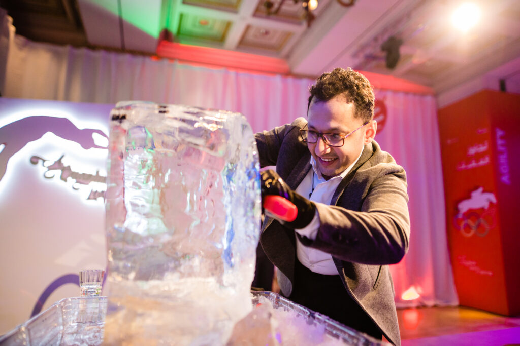 A participant skillfully chisels an ice block during an engaging Team building Ice Sculpting activity, focused on creativity and collaboration.