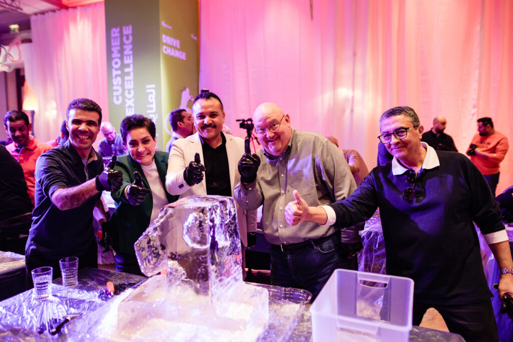 A group of participants gives a thumbs up next to their ice sculpture, celebrating teamwork and creativity during an exciting Team building Ice Sculpting challenge.