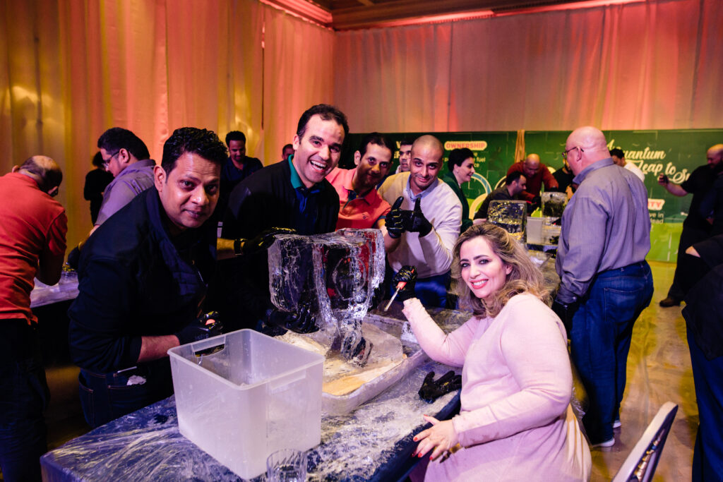 A team enthusiastically works together on their ice sculpting project during a Team building Ice Sculpting event, displaying their creativity and collaboration skills.