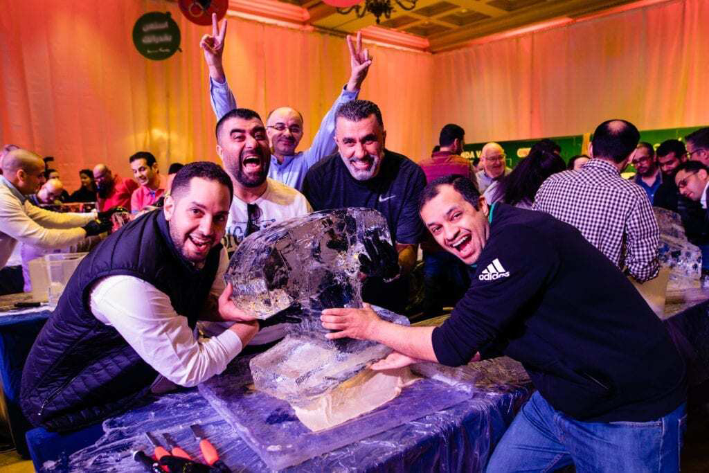 A group of participants eagerly working together to sculpt ice during a Team building Ice Sculpting workshop, showcasing creativity, teamwork, and skill.