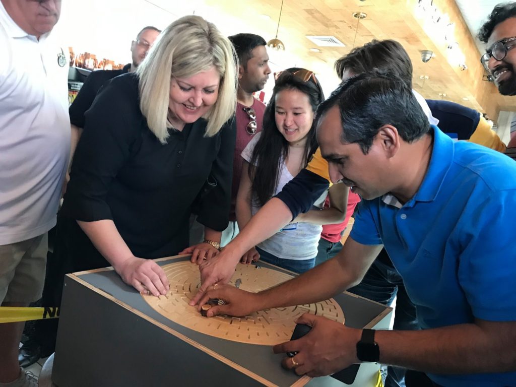 Participants working together to solve a large maze puzzle during the 'Escape The Maze' team building event, showcasing teamwork and problem-solving skills.