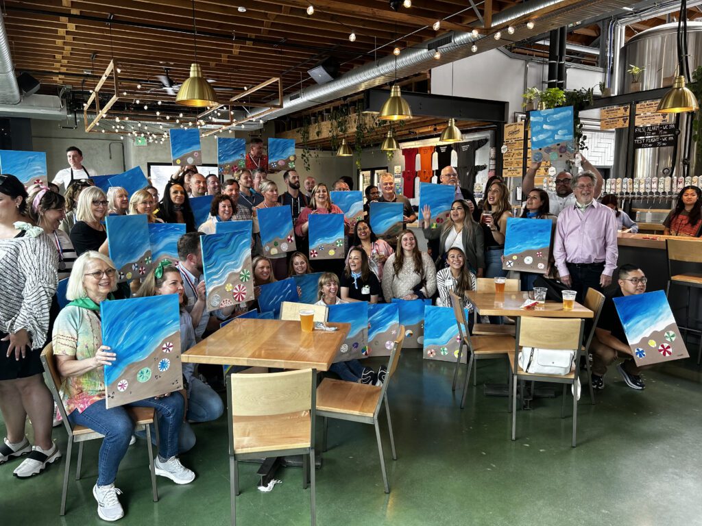 Group showcasing their ocean-inspired paintings after a creative session during a Mystery Bus team building event.