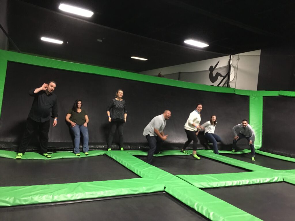 Team members bouncing with joy on trampolines during a Mystery Bus team building event, adding fun and energy to their day of surprises and adventure.