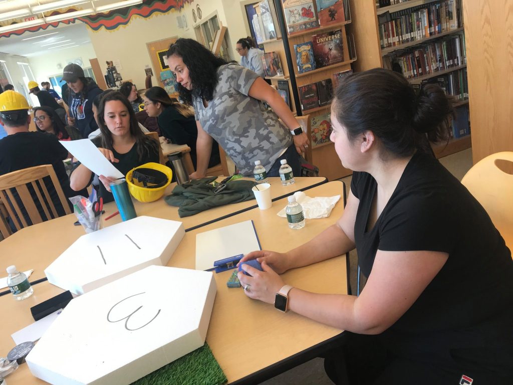 Participants working together at a City Build team building event, preparing materials and brainstorming plans for their collaborative city project.