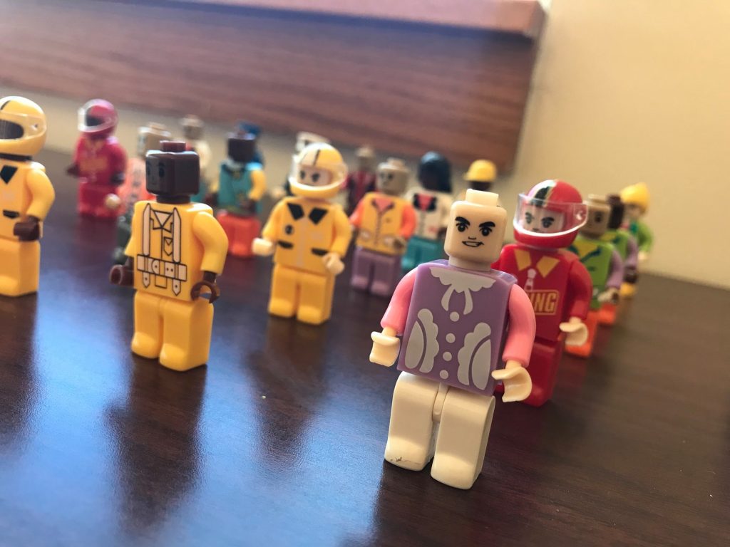 Close-up of colorful mini-figures lined up for use in a City Build team building activity, representing people within the miniature city project.