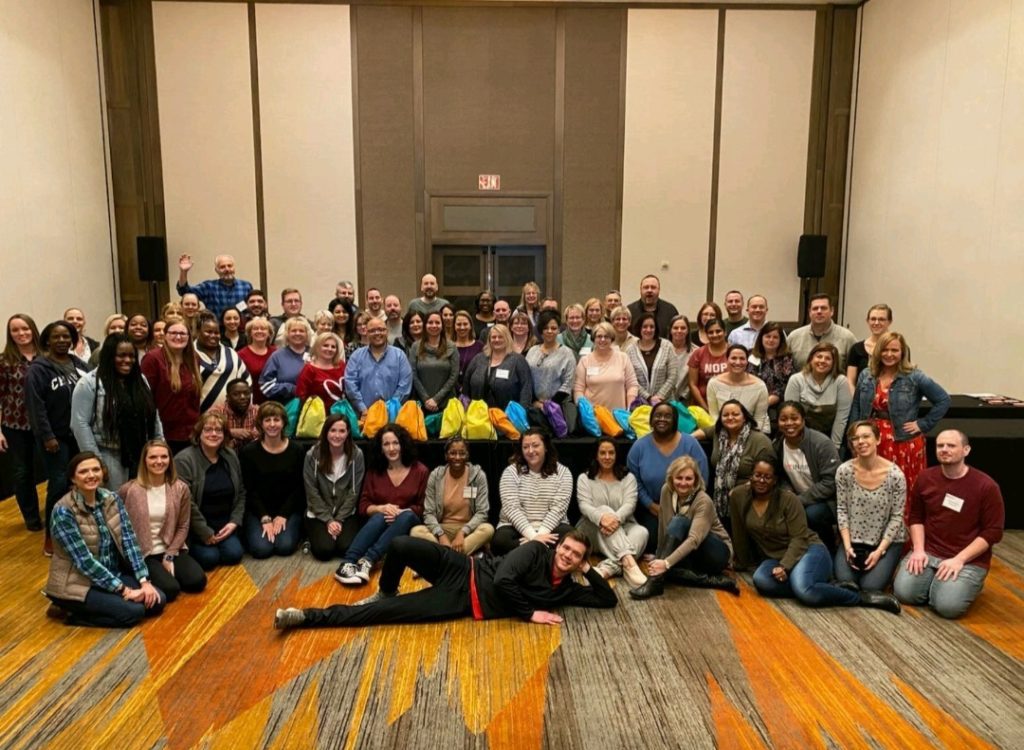 Large group gathered together for the Team Disaster Relief event, proudly holding their colorful bags. They collaborated to assemble disaster relief kits, engaging in teamwork and problem-solving challenges to support recovery efforts.