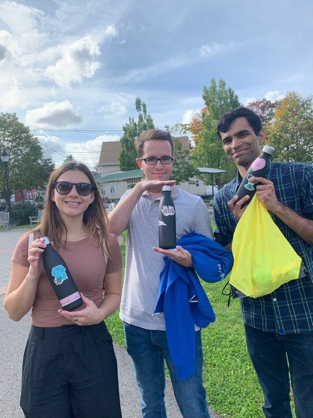 Three participants proudly displaying decorated water bottles and donation bags during the Healthcare Heroes scavenger hunt team building activity.