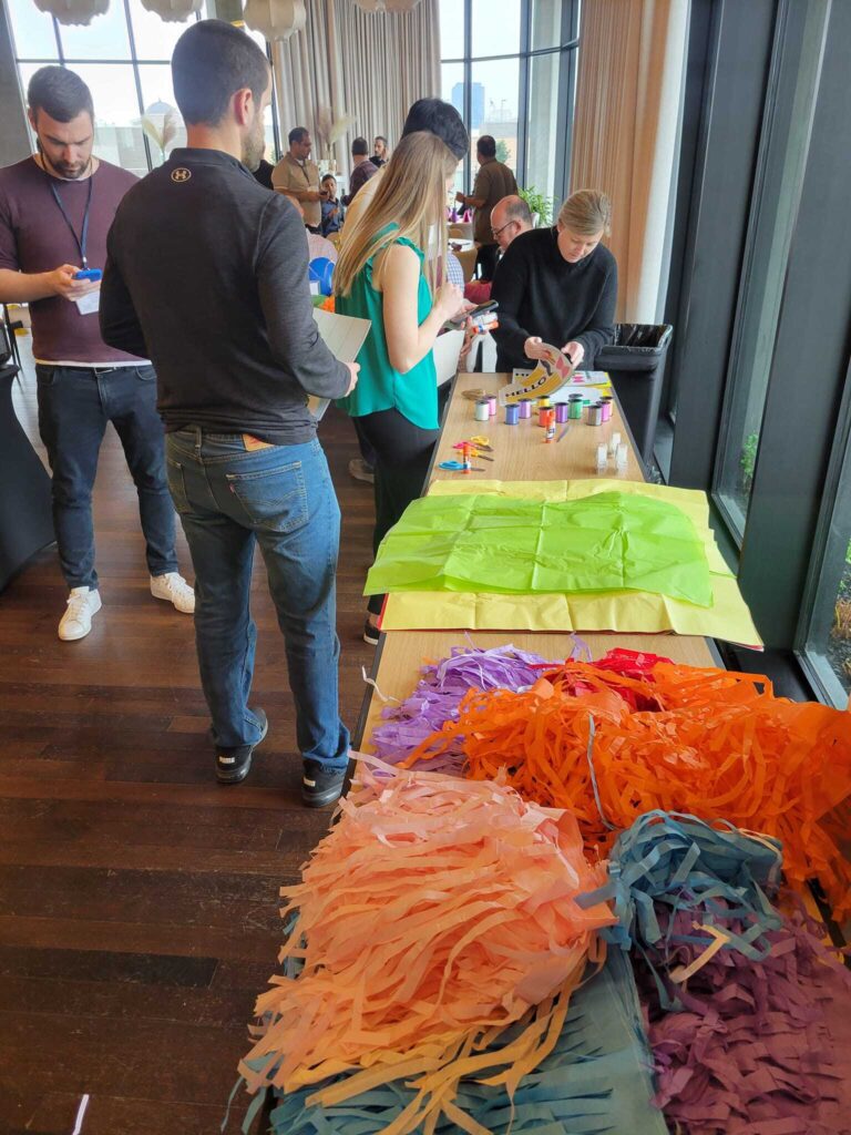 Participants assembling colorful birthday kits with tissue paper, ribbon, and other supplies during a corporate team building event, called 'The Donation Station'.