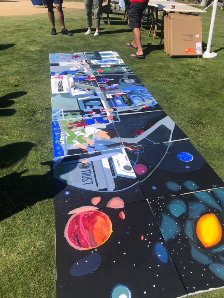 A completed space-themed mural with vibrant images of planets, astronauts, and the word 