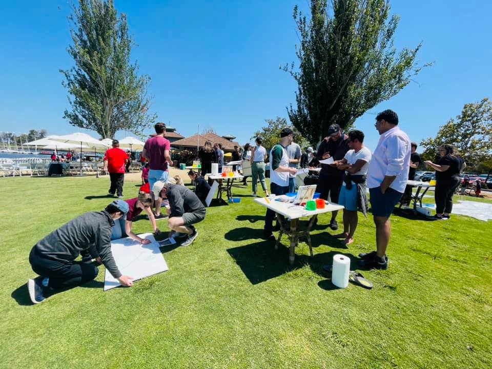 Teams collaborate outdoors on individual canvases during The Big Picture team building event, working together to create a collective mural that promotes communication and teamwork.