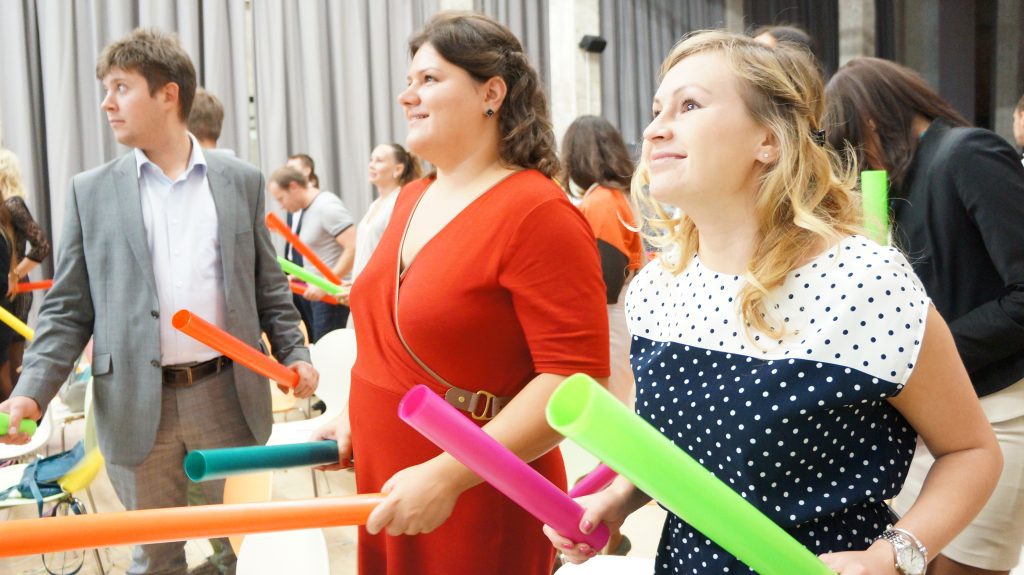 Team members actively participating in Boom Time, a musical team building activity. They collaborate with colorful Boomwhackers to create music, fostering teamwork, energy, and communication.