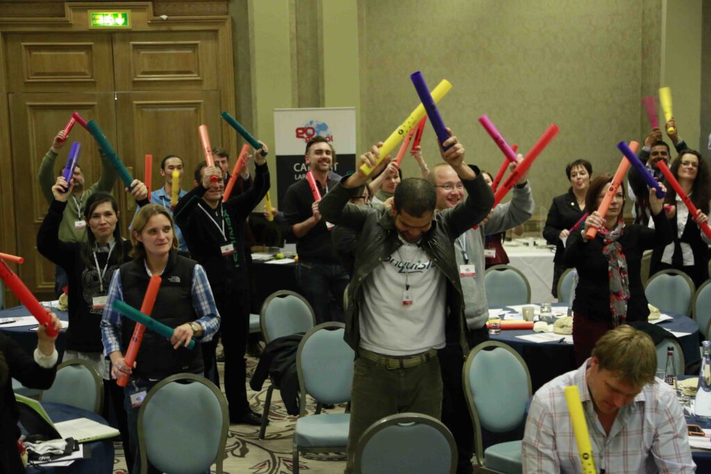 Group of participants enthusiastically playing colorful Boomwhackers in unison during a dynamic team building activity, fostering collaboration and rhythm.