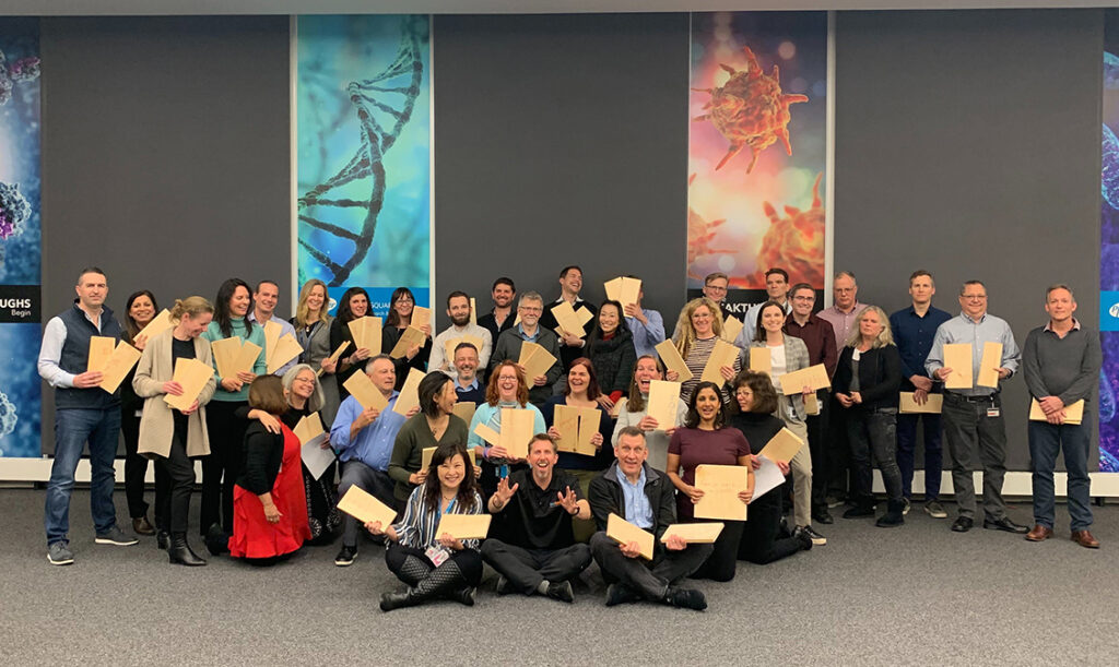 A group of participants proudly holding their broken boards after completing a team building activity focused on overcoming personal and professional barriers.