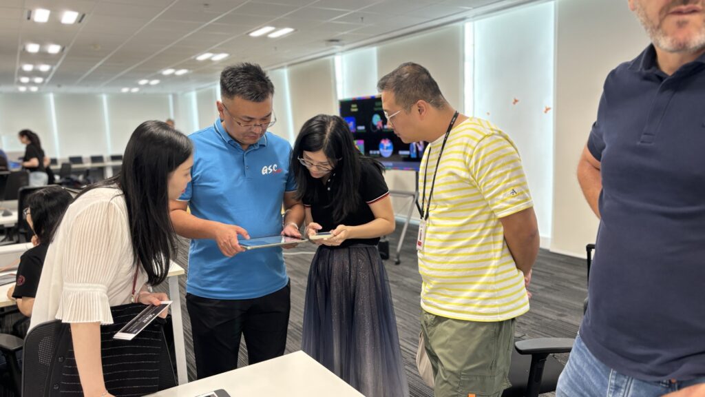 This image showcases a team building event where participants work collaboratively, utilizing tablets to coordinate and create their AI-driven broadcast, exemplifying effective teamwork and communication.