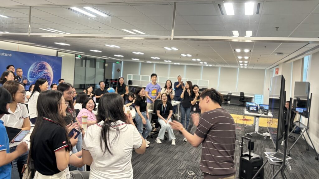 A lively moment during the team building AI news challenge, where participants cheer and applaud as a team presents their final 