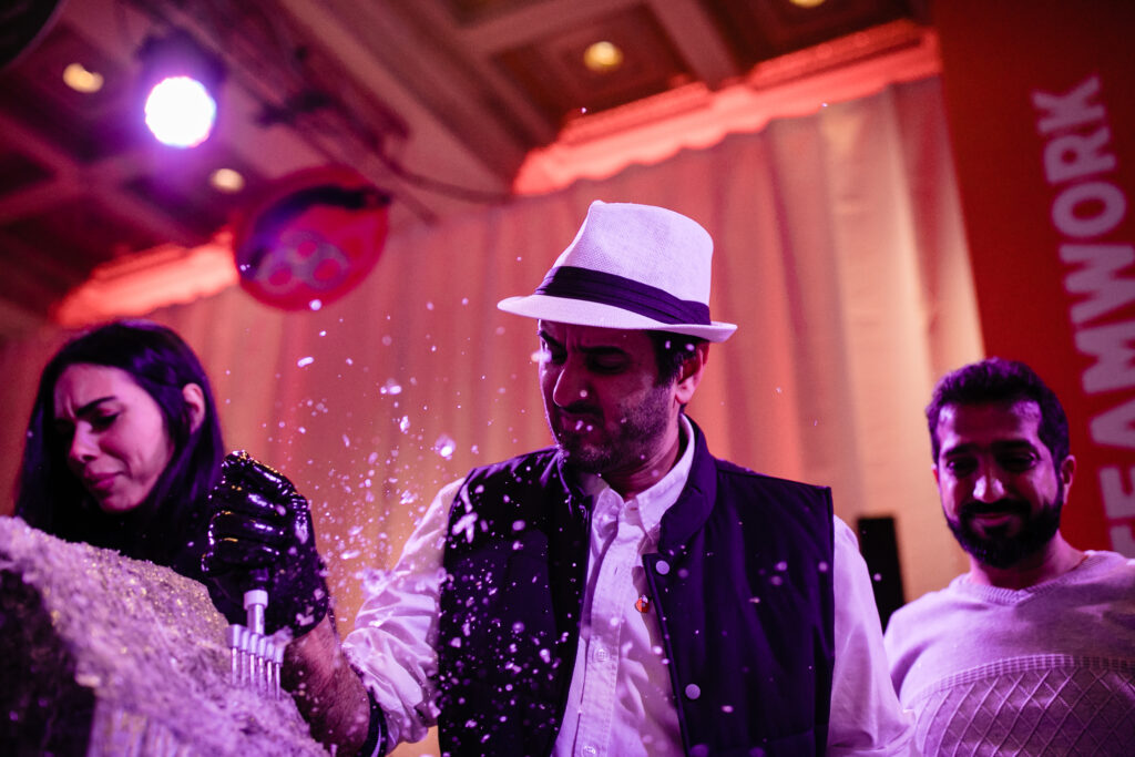 A team collaborates to create an ice sculpture at a Team building Ice Sculpting event, using tools to carefully shape the frozen block into a masterpiece.