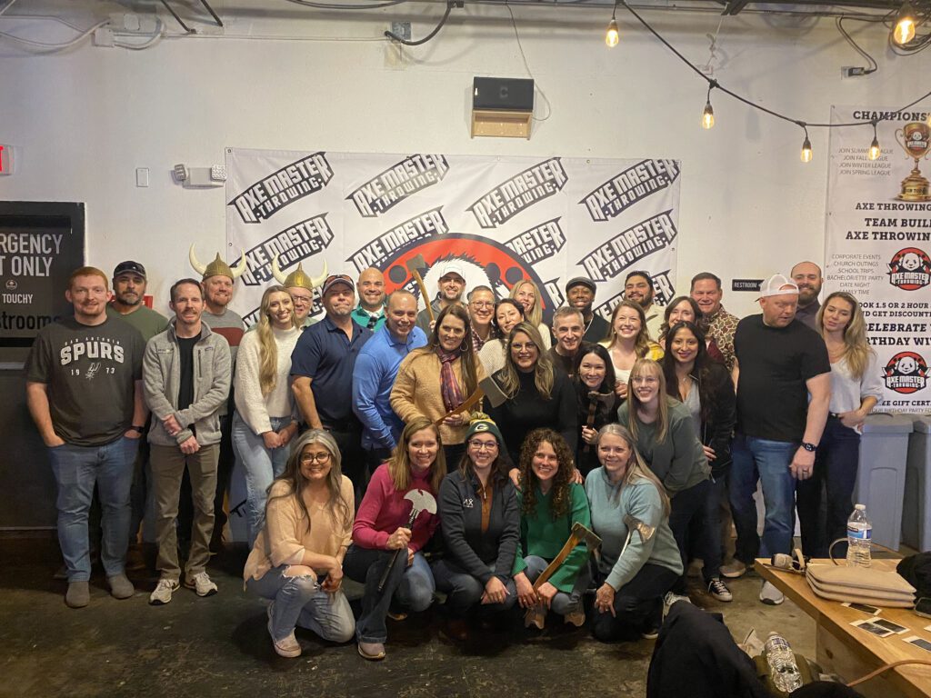 Team posing with axes after a competitive and fun axe-throwing session during a Mystery Bus team building event.