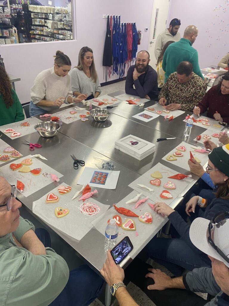 Team decorating heart-shaped cookies during a creative baking stop on the Mystery Bus team building adventure.