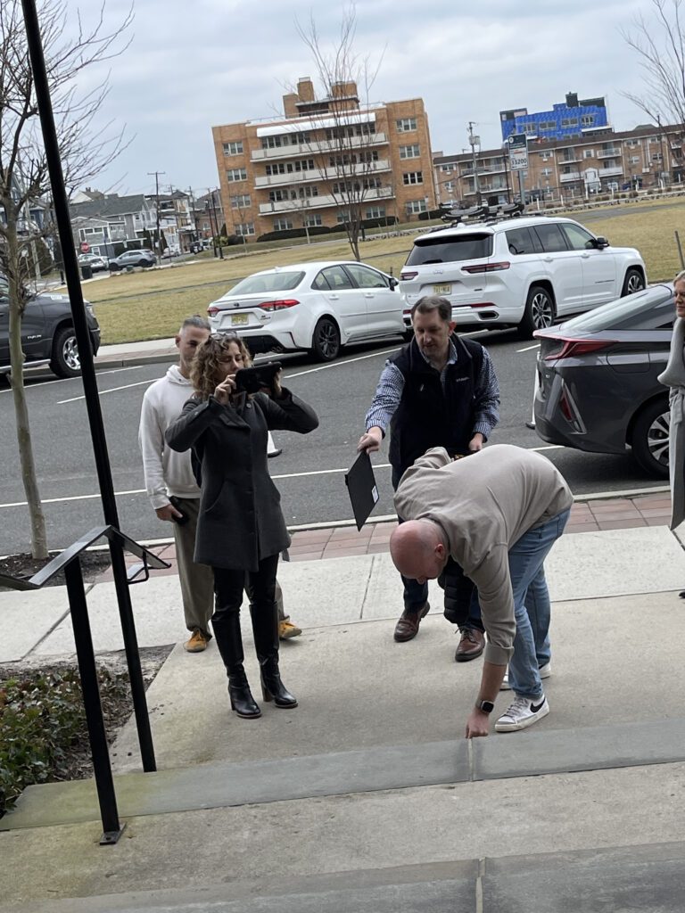 Team members conducting a hands-on outdoor activity, with one person recording one of her team members acting on the Corporate Film Festival team building challenge.