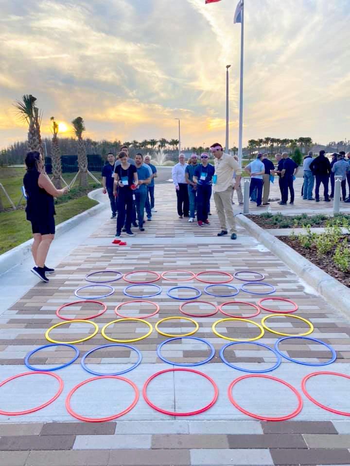 Team members engaging in an outdoor ring toss challenge during a sunset team building activity.