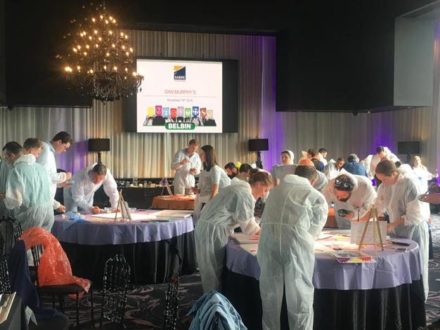 Participants in protective suits collaborate on an activity during the Team and Leadership DNA workshop, working at various stations to build insights and foster team development.