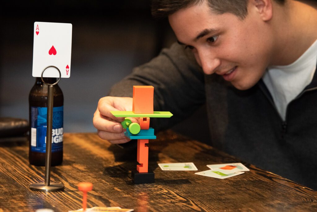 A participant focuses on stacking small game pieces during a business networking team building event designed to spark connections and fun interactions.