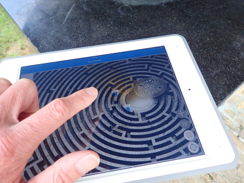 articipant navigates a virtual maze on a tablet during the 'Escape The Maze' team building event, utilizing problem-solving and strategy skills.