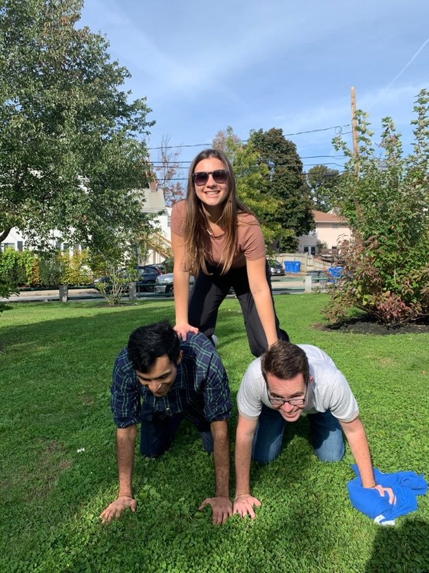 Three participants forming a human pyramid during the Healthcare Heroes scavenger hunt team building program.