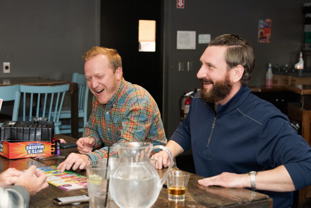 Two team members laugh together while participating in an engaging board game at a team building networking event.