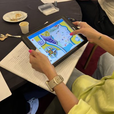 Team building activity using a GPS-enabled iPad for human skills training. A participant navigates challenges and checkpoints, enhancing teamwork, decision-making, and strategic thinking in a dynamic learning experience.