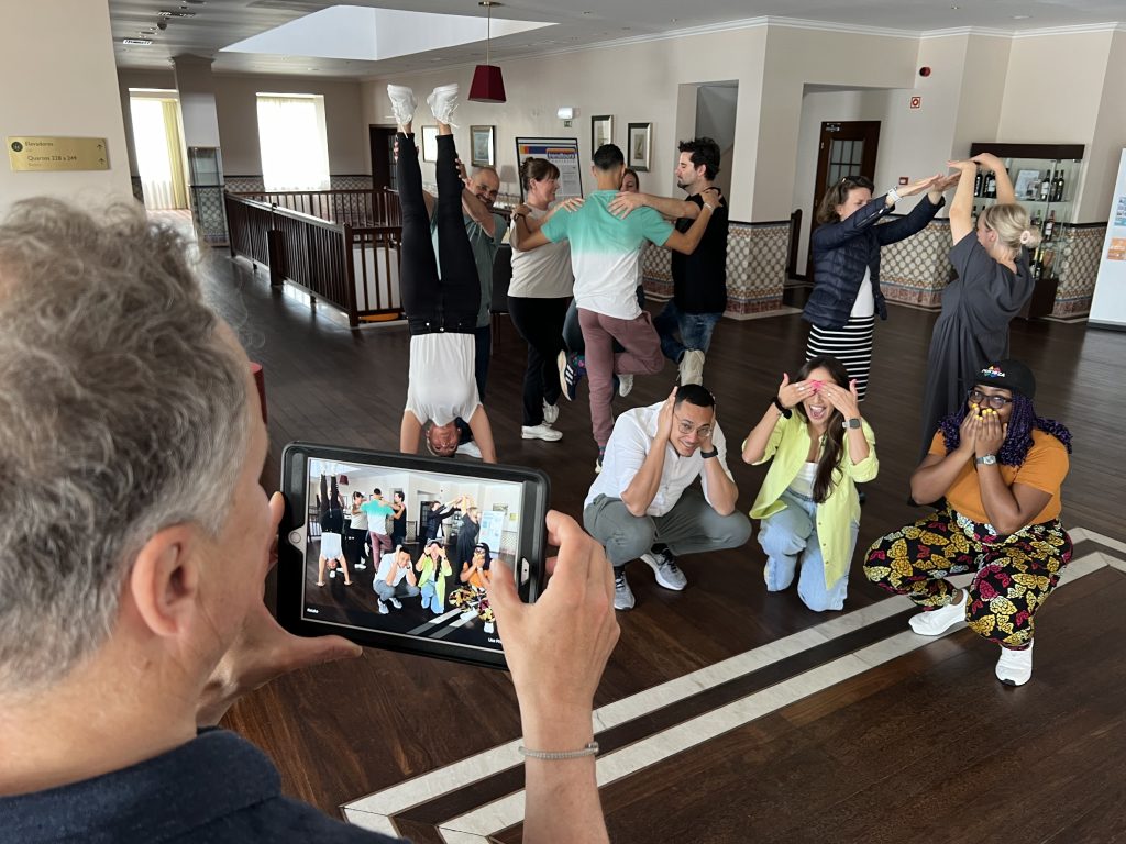 Interactive team building activity focused on human skills training. Participants form creative group poses while a teammate captures the moment, emphasizing collaboration, communication, and teamwork in a fun learning environment.