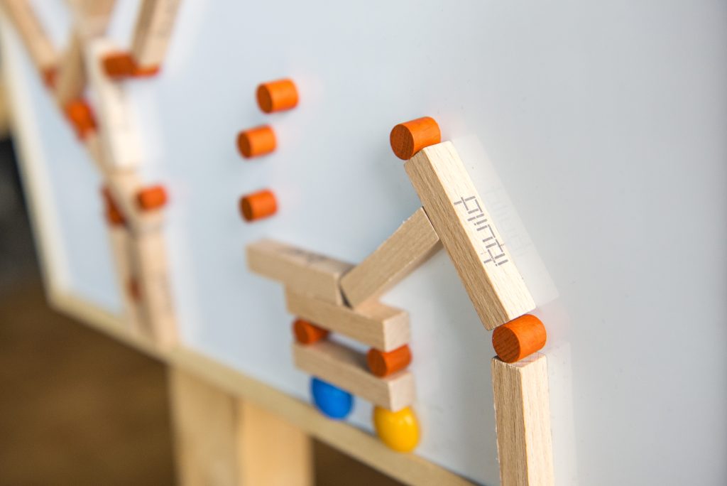 Close-up of an 'ibuild' model from a team building activity. Wooden pieces and connectors form a structure, highlighting the importance of precision, communication, and teamwork in the challenge.