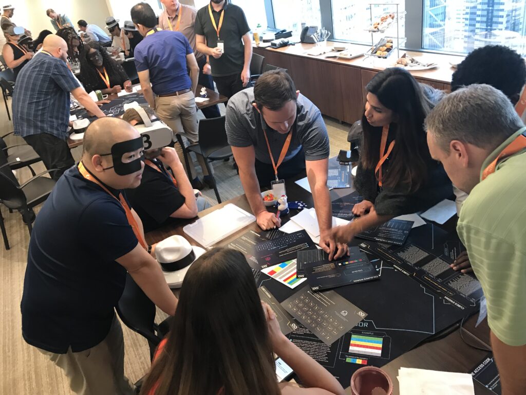 Participants gather around a table during The Infinite Loop team building event, collaborating to solve virtual puzzles as part of a VR-based challenge.