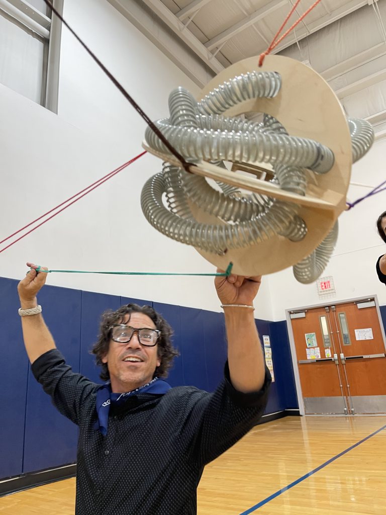 A participant holding a complex structure as part of the Integrity team building event, demonstrating teamwork and balance in a physical challenge.