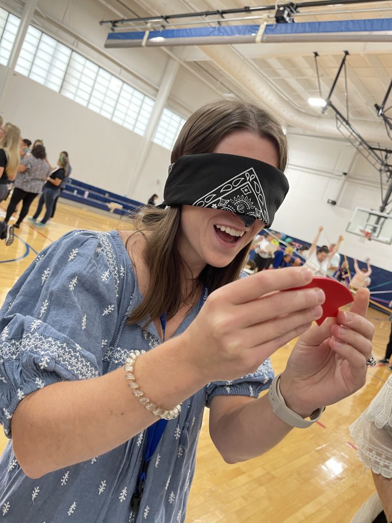 A participant blindfolded and smiling while completing a challenge in the Integrity team building event, focused on teamwork and communication.