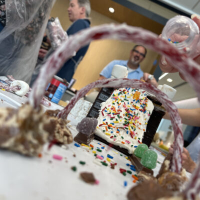 A creative chocolate bridge decorated with sprinkles, candy, and licorice arches, built during The Chocolate Challenge team building event. Participants focus on collaboration and edible engineering.