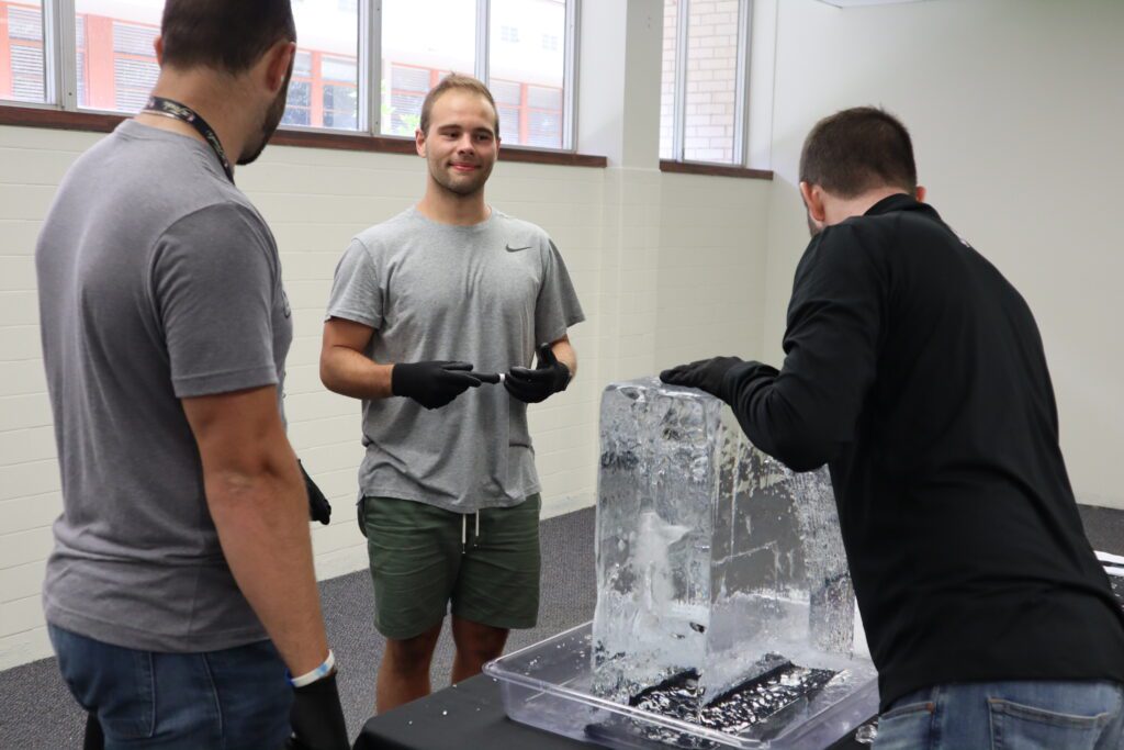 A group of participants works together, chiseling an ice block during a Team building Ice Sculpting event, showcasing teamwork and creativity.