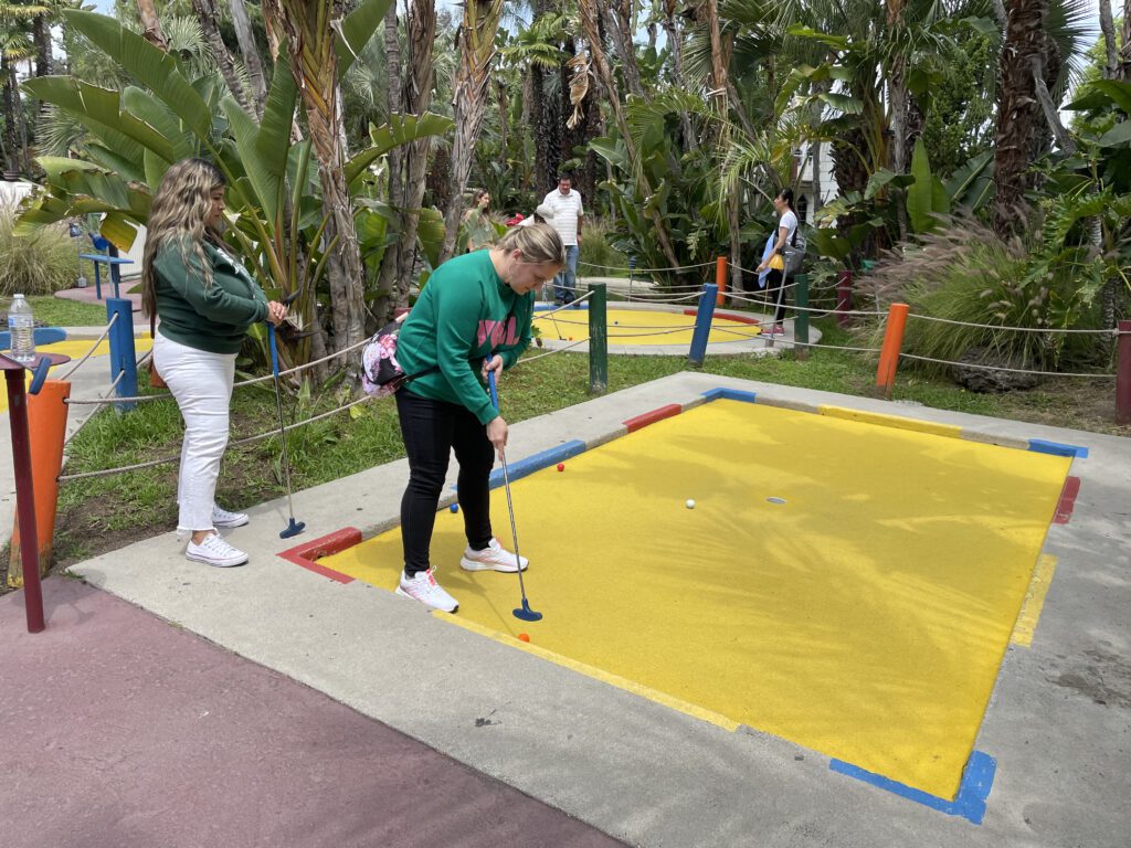 Team member enjoying a mini-golf challenge during a fun-filled stop on the Mystery Bus team building event.